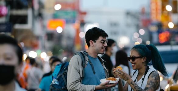 Young tourists enjoy street food amidst bustling city vibes, capturing urban lifestyle.